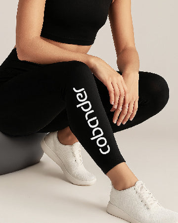 Person wearing black leggings with a brand logo, sitting on a gray ball.